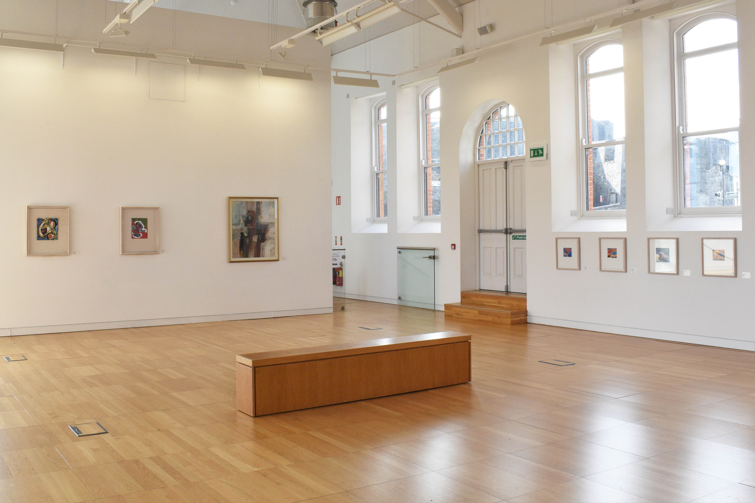 Art on walls with a bench at the exhibition Symbols of Subject at Luan Gallery