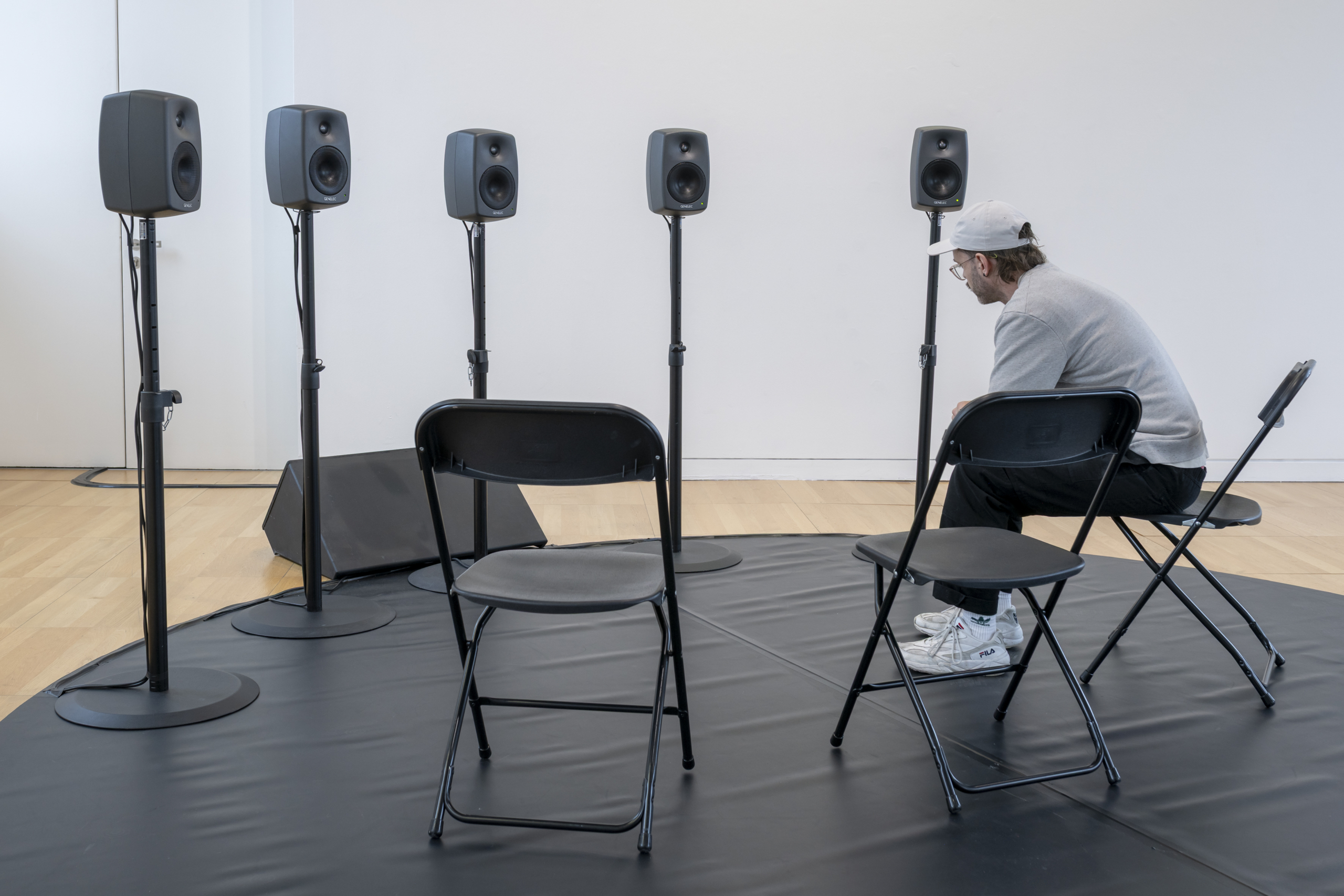 Speakers in a half cirkel with chairs and a listener at the exhibition System Arming at Luan Gallery