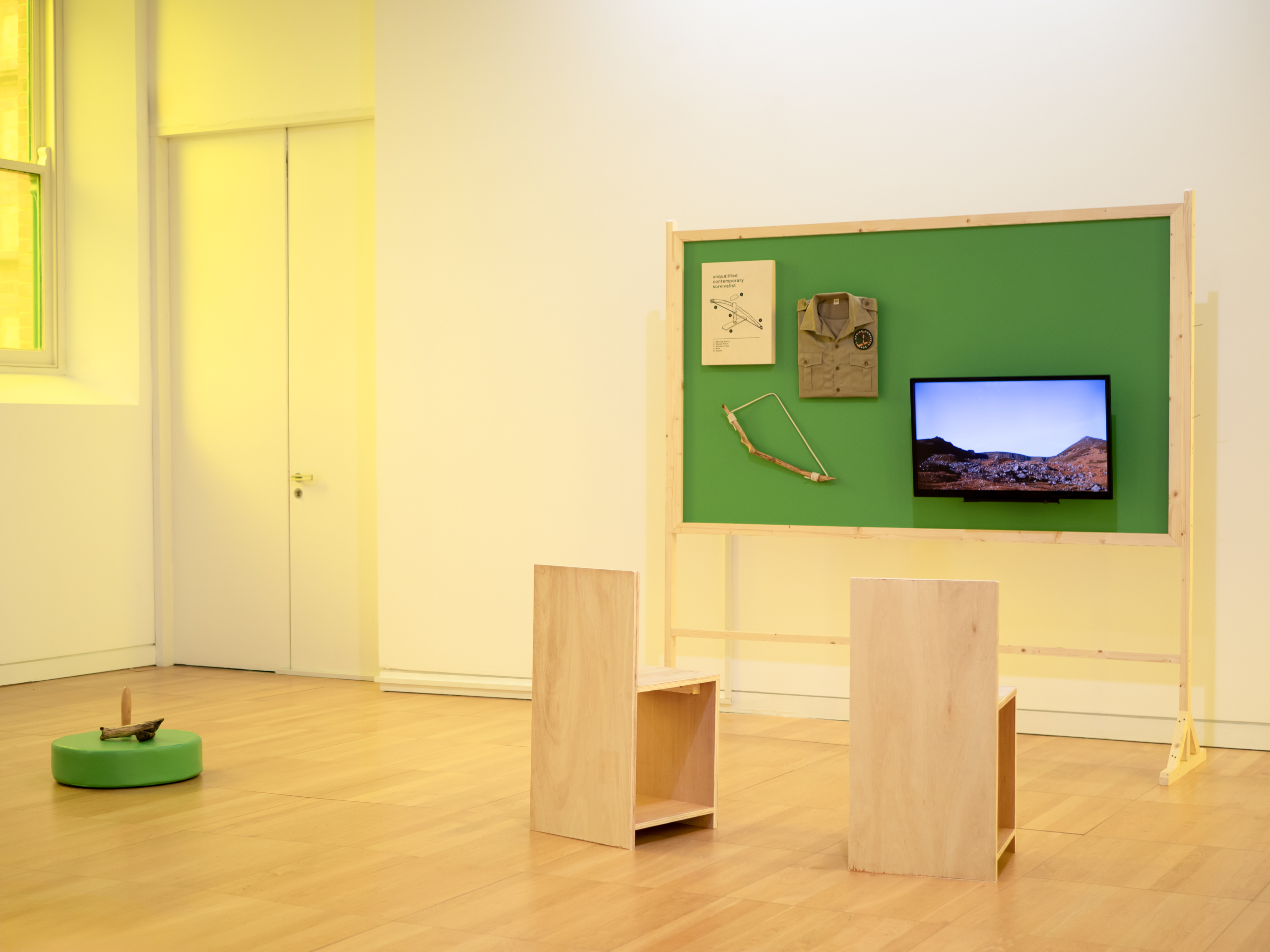 Green board with legs with screen and art on it, at the exhibition Apocalypse Anxieties at Luan Gallery