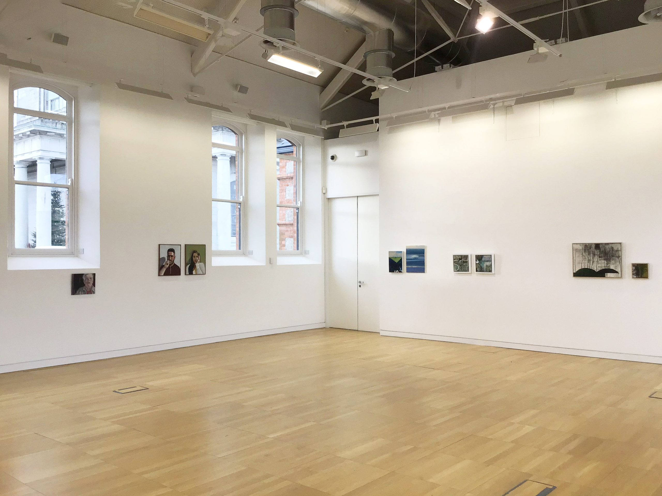 Art in a white room with a wooden floor at Luan Gallery